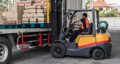 warehouse worker in a forklift loading a flatbed truck