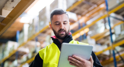 Warehouse employee with safety gear checking a tablet